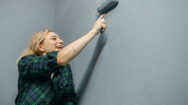 Lady smiling, painting a room