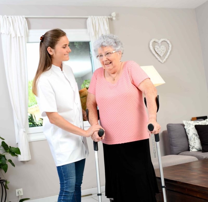 Physio assisting lady walking with elbow crutches